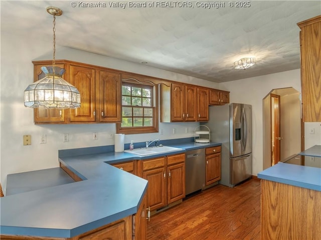 3710 Cambridge Cir, Hurricane, WV 25526 - kitchen featuring stainless steel appliances, brown cabinetry, wood finished floors, pendant lighting, and a peninsula