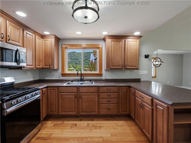 9012 Florida Ave, Marmet, WV 25315 - kitchen with appliances with stainless steel finishes, dark countertops, a peninsula, light wood finished floors, and brown cabinetry