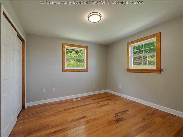9012 Florida Ave, Marmet, WV 25315 - unfurnished bedroom with multiple windows, light wood finished floors, and a closet