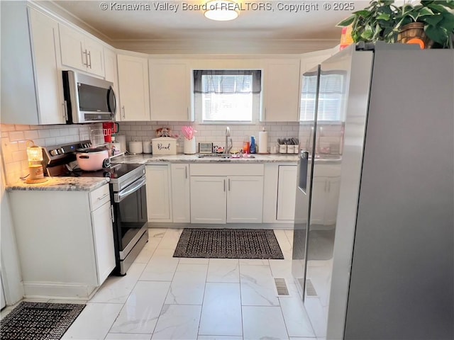602 43rd St SE, Charleston, WV 25304 - kitchen featuring appliances with stainless steel finishes, white cabinets, light marble finish flooring, decorative backsplash, and light stone counters