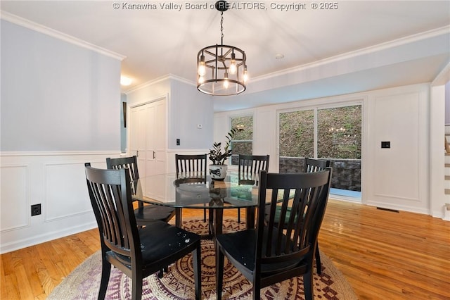 815 Chappell Rd, Charleston, WV 25304 - dining room with light wood finished floors, a decorative wall, a chandelier, ornamental molding, and a wainscoted wall