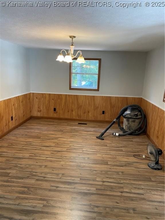 42 Pine Cone Rd, Elkview, WV 25071 - empty room featuring a wainscoted wall, wood finished floors, wooden walls, a chandelier, and a textured ceiling