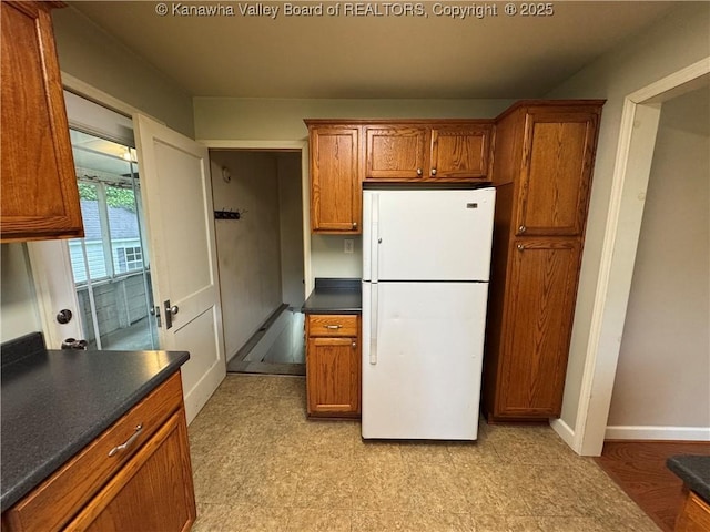913 Charleston Rd, Point Pleasant, WV 25550 - kitchen with freestanding refrigerator, dark countertops, brown cabinetry, and light floors