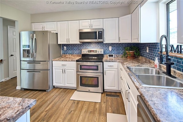 5301 Balsam Cir, Charleston, WV 25313 - kitchen featuring appliances with stainless steel finishes, light wood finished floors, white cabinets, and tasteful backsplash