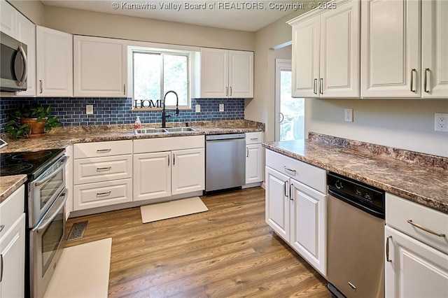5301 Balsam Cir, Charleston, WV 25313 - kitchen featuring appliances with stainless steel finishes, decorative backsplash, light wood-style flooring, white cabinets, and healthy amount of natural light