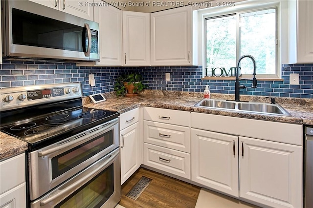5301 Balsam Cir, Charleston, WV 25313 - kitchen featuring appliances with stainless steel finishes, white cabinetry, dark wood finished floors, and tasteful backsplash