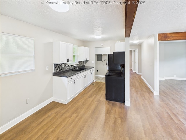 61 Sol Ln, Charleston, WV 25312 - kitchen featuring dark countertops, white cabinets, light wood-style floors, a textured ceiling, and decorative backsplash
