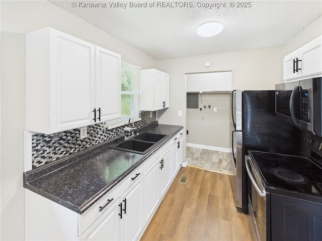 61 Sol Ln, Charleston, WV 25312 - kitchen with stainless steel microwave, electric stove, light wood-style flooring, white cabinetry, and dark countertops