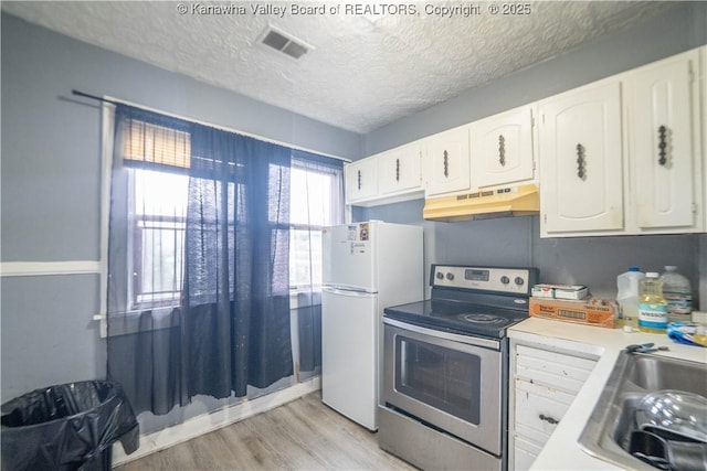 512 Maxwell St, Charleston, WV 25311 - kitchen featuring stainless steel range with electric cooktop, under cabinet range hood, freestanding refrigerator, white cabinets, and light wood finished floors