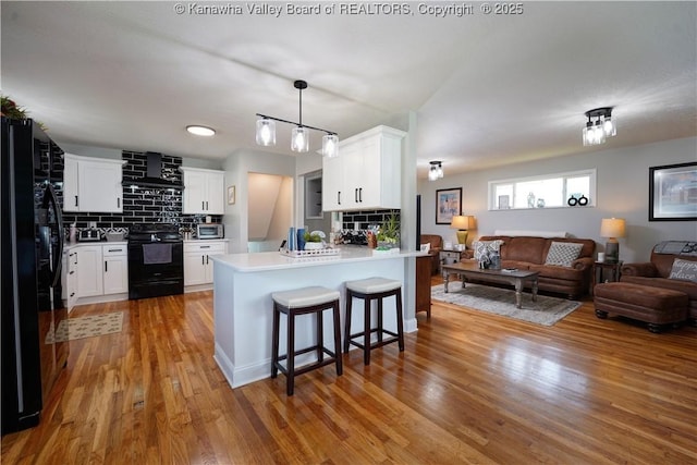 1204 Highland Dr, Saint Albans, WV 25177 - kitchen with black appliances, open floor plan, range hood, a peninsula, and light wood finished floors