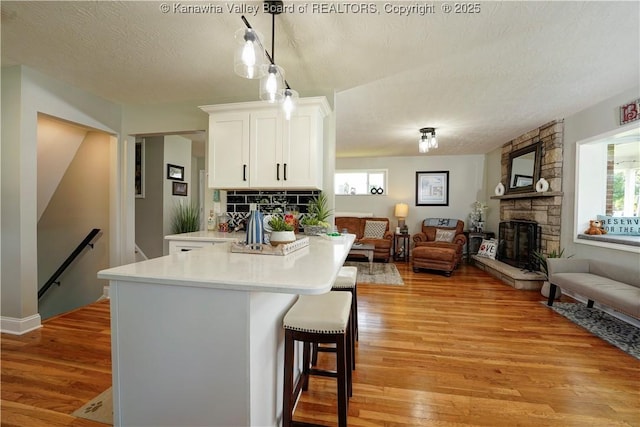 1204 Highland Dr, Saint Albans, WV 25177 - kitchen with open floor plan, a stone fireplace, light wood-style flooring, white cabinetry, and light countertops