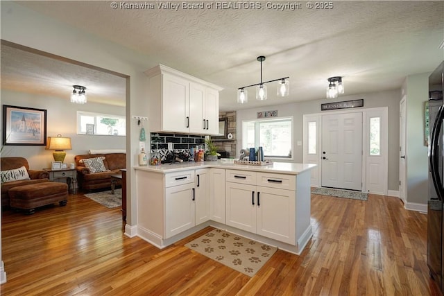 1204 Highland Dr, Saint Albans, WV 25177 - kitchen with a peninsula, light countertops, light wood-style floors, decorative backsplash, and a textured ceiling