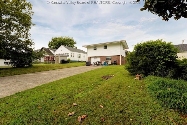 1204 Highland Dr, Saint Albans, WV 25177 - rear view of house with a garage, driveway, brick siding, and a yard