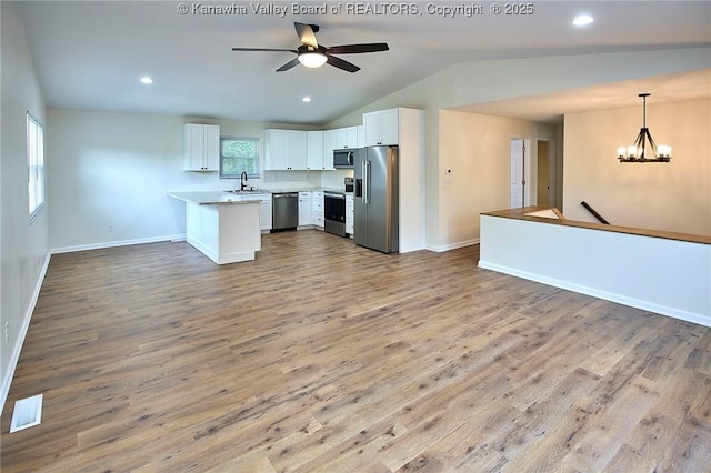 4013 Seymour Ln, Charleston, WV 25313 - kitchen with stainless steel appliances, open floor plan, light countertops, vaulted ceiling, and white cabinetry