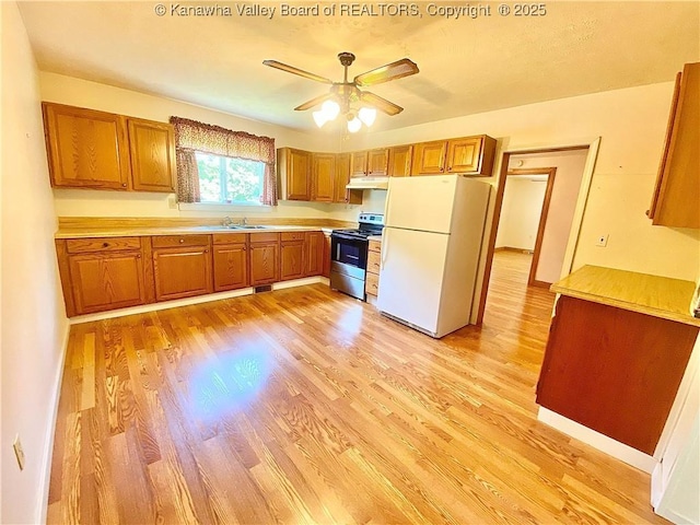 391 River Rd, Racine, WV 25165 - kitchen with stainless steel range with electric cooktop, freestanding refrigerator, under cabinet range hood, and brown cabinets