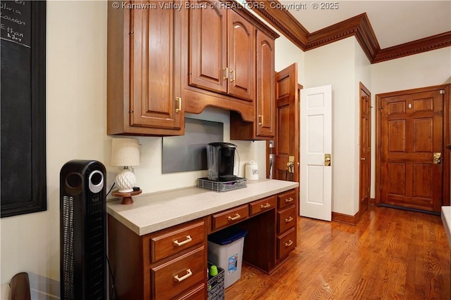 135 E Ridge Rd, Charleston, WV 25314 - kitchen featuring ornamental molding, light countertops, built in desk, light wood-type flooring, and brown cabinets