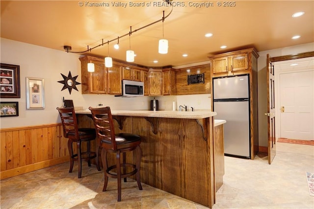135 E Ridge Rd, Charleston, WV 25314 - kitchen with freestanding refrigerator, a peninsula, wainscoting, a breakfast bar, and light countertops