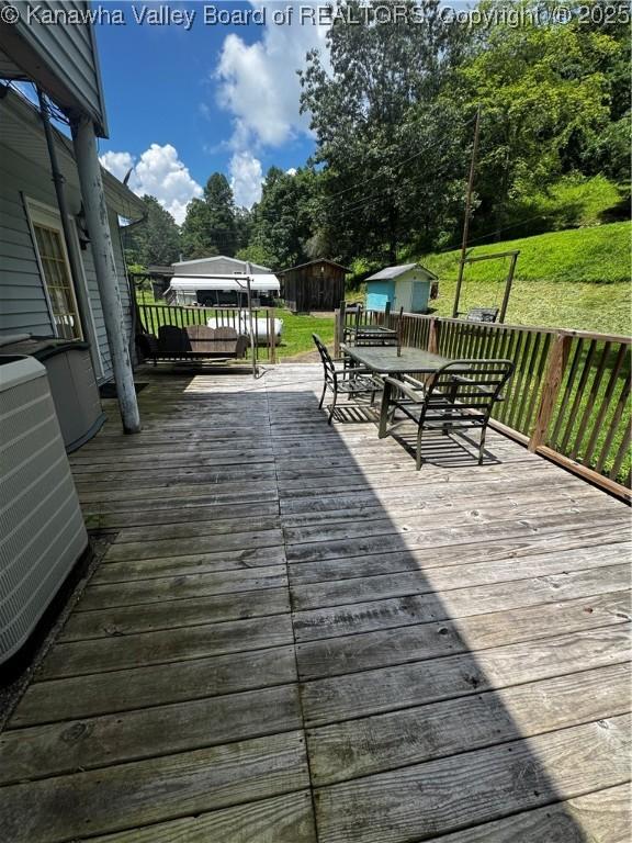 1198 Caney Branch Rd, Chapmanville, WV 25508 - wooden deck with a shed, outdoor dining area, a lawn, and view of scattered trees