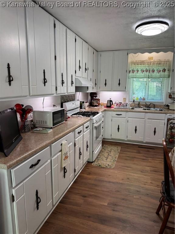 1198 Caney Branch Rd, Chapmanville, WV 25508 - kitchen featuring white range with gas stovetop, black microwave, under cabinet range hood, dark wood-style floors, and white cabinets
