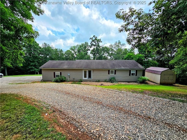 438 Tanglewood Dr, Point Pleasant, WV 25550 - ranch-style house with a storage unit, driveway, view of scattered trees, and a front lawn