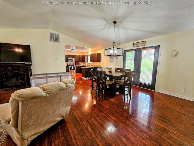 438 Tanglewood Dr, Point Pleasant, WV 25550 - dining space featuring dark wood-style flooring, vaulted ceiling, a chandelier, and a glass covered fireplace