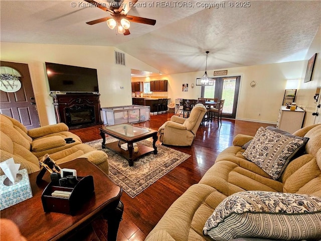 438 Tanglewood Dr, Point Pleasant, WV 25550 - living area with vaulted ceiling, a ceiling fan, dark wood-style flooring, a glass covered fireplace, and a textured ceiling