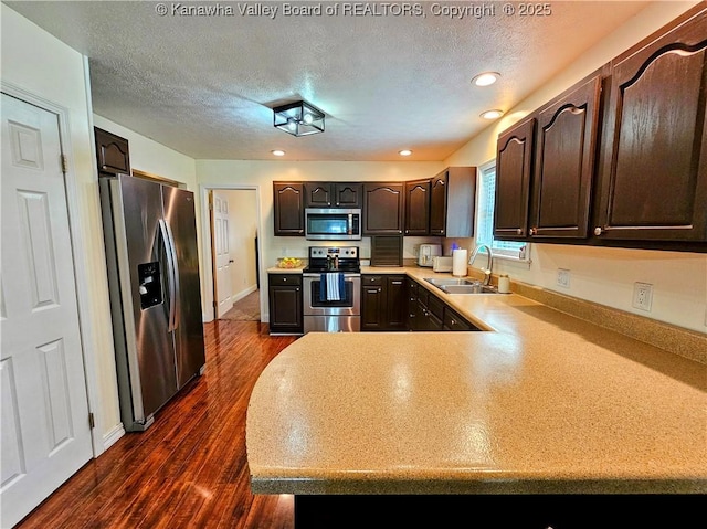 438 Tanglewood Dr, Point Pleasant, WV 25550 - kitchen with appliances with stainless steel finishes, dark brown cabinetry, light countertops, a peninsula, and dark wood-style floors