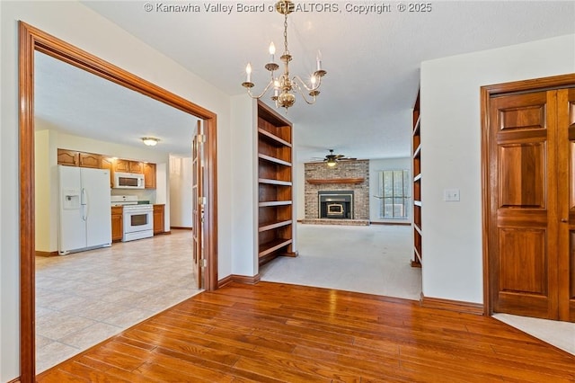 182 Summer Dr, Culloden, WV 25510 - unfurnished dining area featuring a chandelier, a brick fireplace, ceiling fan, and light wood-type flooring