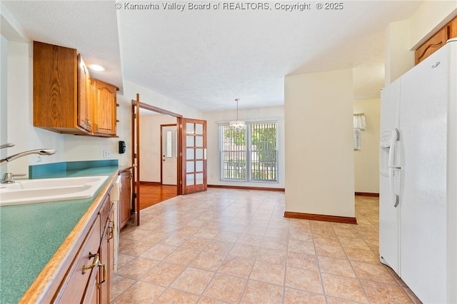 182 Summer Dr, Culloden, WV 25510 - kitchen with white refrigerator with ice dispenser, brown cabinetry, a chandelier, hanging light fixtures, and light countertops