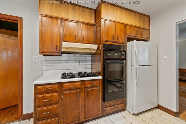 51 Roland Park Dr, Huntington, WV 25705 - kitchen with black appliances, under cabinet range hood, backsplash, brown cabinets, and light countertops