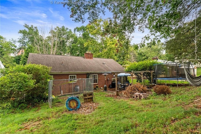 51 Roland Park Dr, Huntington, WV 25705 - rear view of property with a trampoline, brick siding, a chimney, and view of wooded area