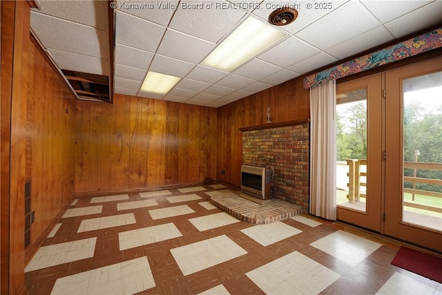 5126 Big Tyler Rd, Cross Lanes, WV 25313 - unfurnished living room with wooden walls, a drop ceiling, a brick fireplace, heating unit, and light floors