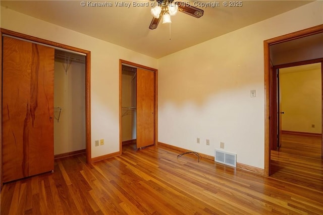 5126 Big Tyler Rd, Cross Lanes, WV 25313 - unfurnished bedroom featuring two closets, wood finished floors, and a ceiling fan