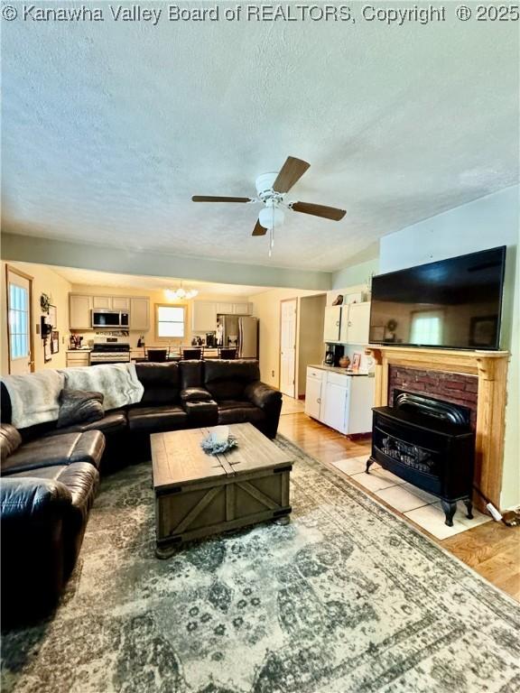 28 Brushy Frk, Alkol, WV 25501 - living area featuring a wood stove, a textured ceiling, ceiling fan, and light wood-type flooring