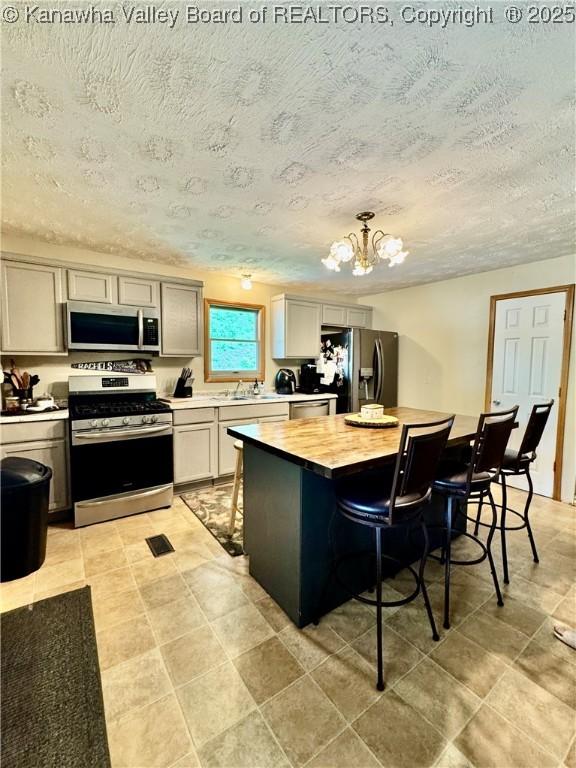 28 Brushy Frk, Alkol, WV 25501 - kitchen with stainless steel appliances, a breakfast bar, a chandelier, butcher block countertops, and a textured ceiling