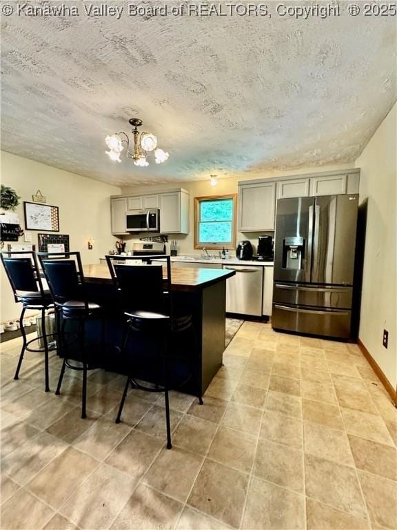 28 Brushy Frk, Alkol, WV 25501 - kitchen featuring appliances with stainless steel finishes, a chandelier, a textured ceiling, a center island, and light tile patterned flooring