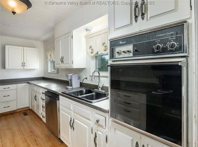 105 Lincoln Hts, Alum Creek, WV 25003 - kitchen featuring black oven, white cabinetry, stainless steel dishwasher, light wood finished floors, and dark countertops