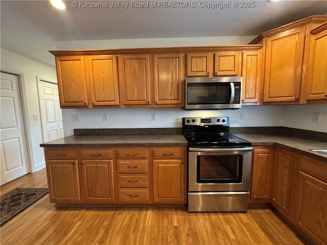 2314 Harrison Ave, Saint Albans, WV 25177 - kitchen with stainless steel appliances, dark countertops, brown cabinetry, and light wood finished floors