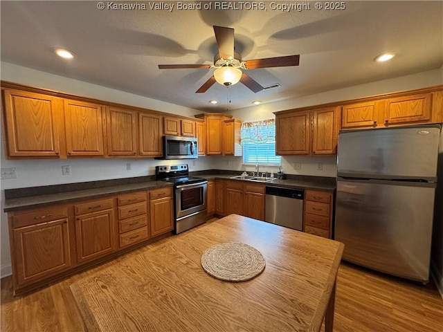 2314 Harrison Ave, Saint Albans, WV 25177 - kitchen featuring stainless steel appliances, brown cabinetry, dark countertops, a ceiling fan, and light wood-style flooring