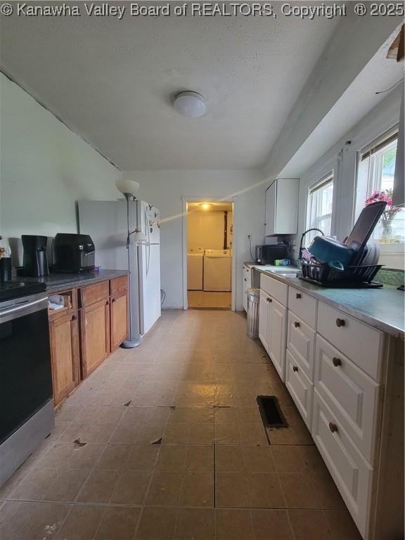 1832 Roxalana Rd, Dunbar, WV 25064 - kitchen with independent washer and dryer, stainless steel electric range oven, freestanding refrigerator, white cabinets, and tile patterned floors