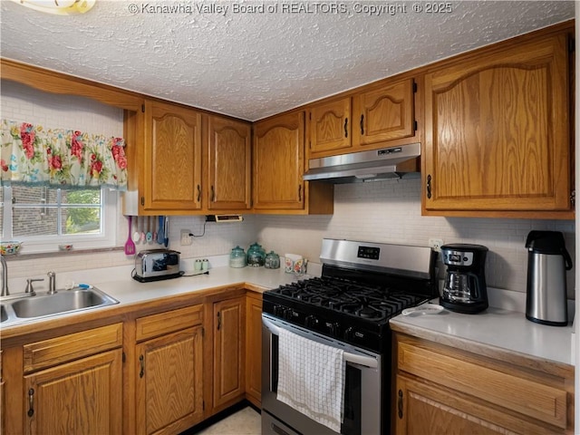 4728 Cain Ridge Rd, Leon, WV 25123 - kitchen with gas range, under cabinet range hood, brown cabinetry, decorative backsplash, and a textured ceiling