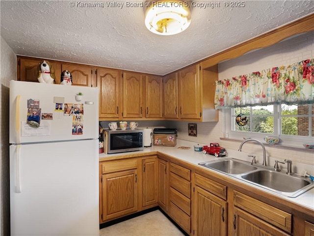 4728 Cain Ridge Rd, Leon, WV 25123 - kitchen featuring freestanding refrigerator, light countertops, stainless steel microwave, a textured ceiling, and brown cabinetry