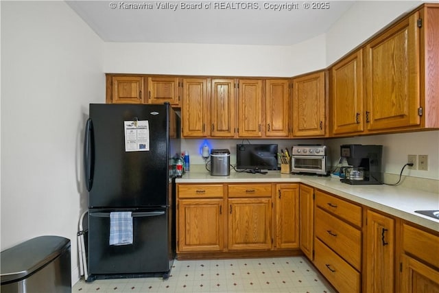 2526 Spring St, South Charleston, WV 25303 - kitchen with freestanding refrigerator, light countertops, brown cabinetry, and light floors