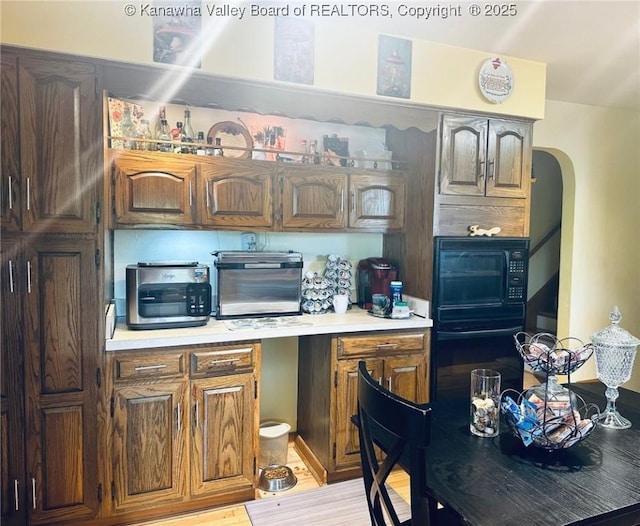 1816 Winding Hill Dr, Sissonville, WV 25320 - kitchen featuring light countertops, arched walkways, black appliances, and light wood-style flooring