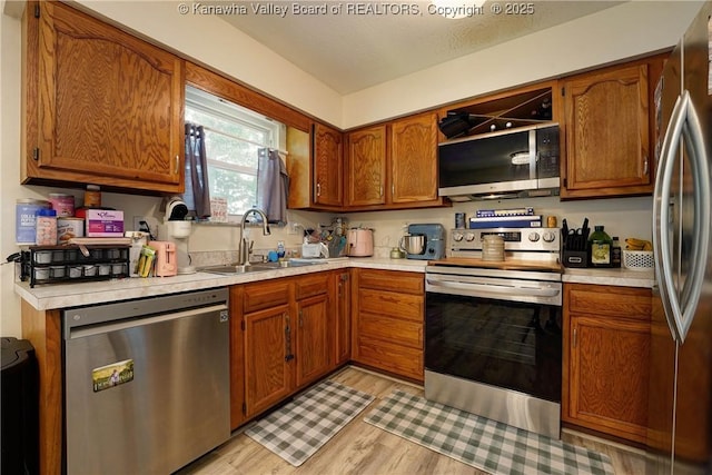 51 Beaver Dr, Hurricane, WV 25526 - kitchen featuring appliances with stainless steel finishes, light countertops, light wood-style floors, and brown cabinetry