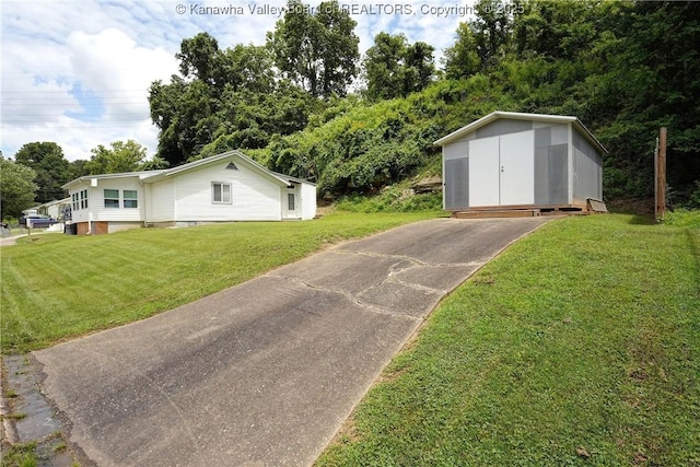 1009 Midway Dr, Dunbar, WV 25064 - view of front facade featuring a storage unit, a front lawn, asphalt driveway, and view of wooded area