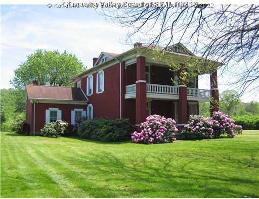 view of home's exterior featuring a balcony and a yard