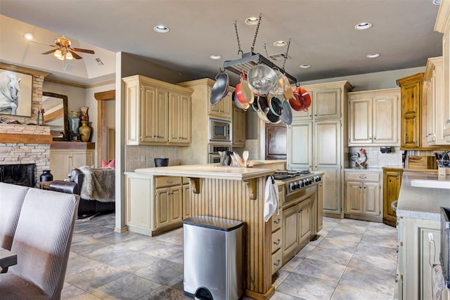 kitchen featuring a breakfast bar, a center island, ceiling fan, decorative backsplash, and stainless steel appliances