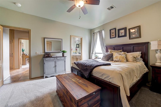 bedroom featuring ceiling fan, light colored carpet, and connected bathroom