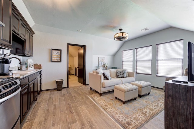 living room featuring sink, vaulted ceiling, and light wood-type flooring